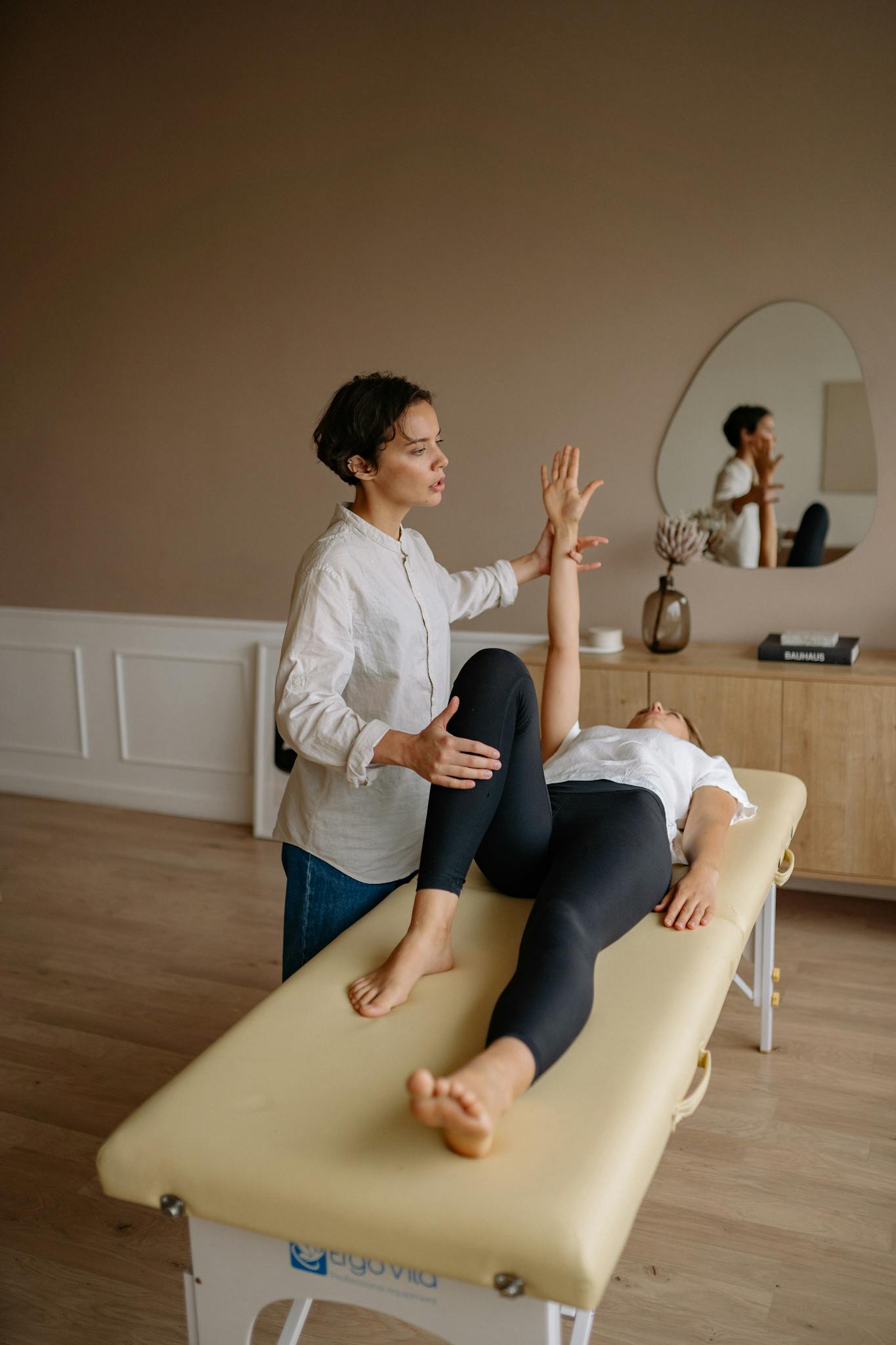 A therapist assists a patient during a physical therapy session indoors, focusing on rehabilitation.